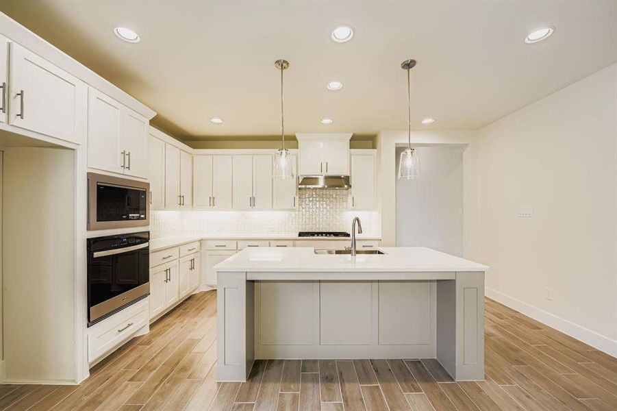 Kitchen with oven, recessed lighting, wood tiled floors, backsplash, and white cabinetry