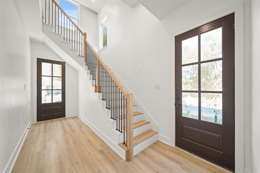 Grand entryway featuring high ceilings, LVP floors, and a spectacular stair case. Photos are from a similar unit in the development.