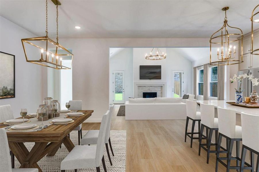 Dining area with a chandelier, a fireplace, light wood-style flooring, recessed lighting, and vaulted ceiling Dining area with a chandelier, a fireplace, light wood-style flooring, recessed lighting, and vaulted ceiling