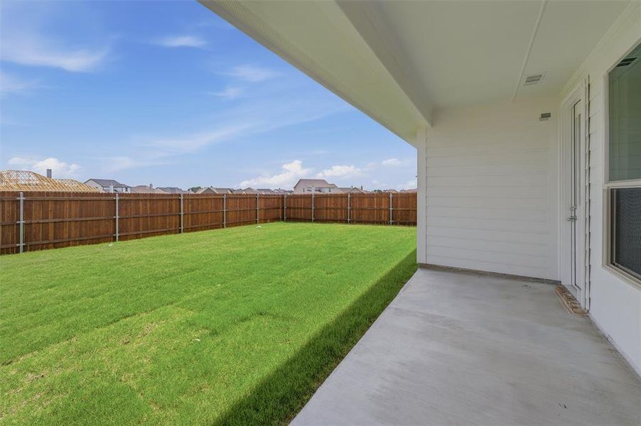 Expansive backyard featuring a manicured lawn, full privacy fencing, and a concrete patio Expansive backyard featuring a manicured lawn, full privacy fencing, and a concrete patio