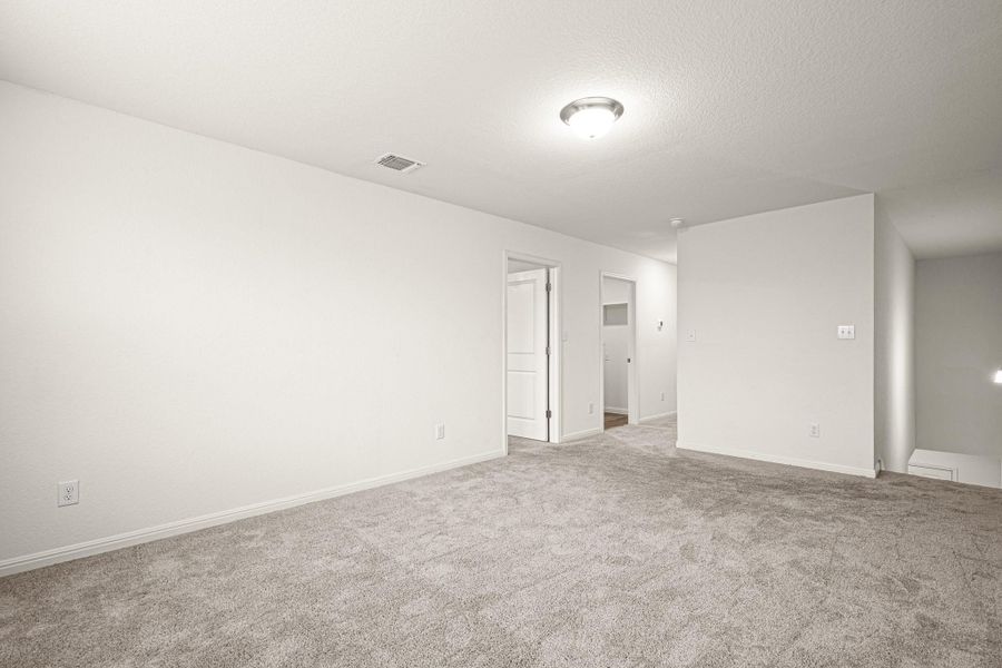 Empty room with light carpet and a textured ceiling