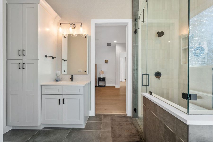 Full bath with vanity, a shower stall, and dark tile patterned flooring