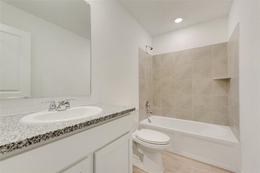 Full bathroom with vanity, tiled shower / bath combo, wood-type flooring, and toilet