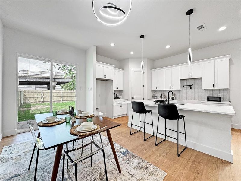 Kitchen featuring an island with sink, white cabinets, light wood-style flooring, light countertops, and recessed lighting