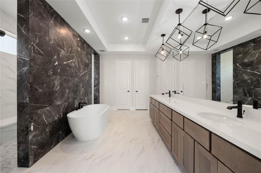 Spa-like primary ensuite bathroom showcasing a dramatic, ultra-modern design. This luxurious retreat centers around an elegant freestanding soaking tub set against a stunning floor-to-ceiling dark marble-patterned accent wall. The expansive double-sink vanity offers sleek white quartz countertops, contemporary matte black plumbing fixtures, and custom geometric open-cage pendant lighting. This bathroom delivers ultimate everyday luxury. Spa-like primary ensuite bathroom showcasing a dramatic, ultra-modern design. This luxurious retreat centers around an elegant freestanding soaking tub set against a stunning floor-to-ceiling dark marble-patterned accent wall. The expansive double-sink vanity offers sleek white quartz countertops, contemporary matte black plumbing fixtures, and custom geometric open-cage pendant lighting. This bathroom delivers ultimate everyday luxury.
