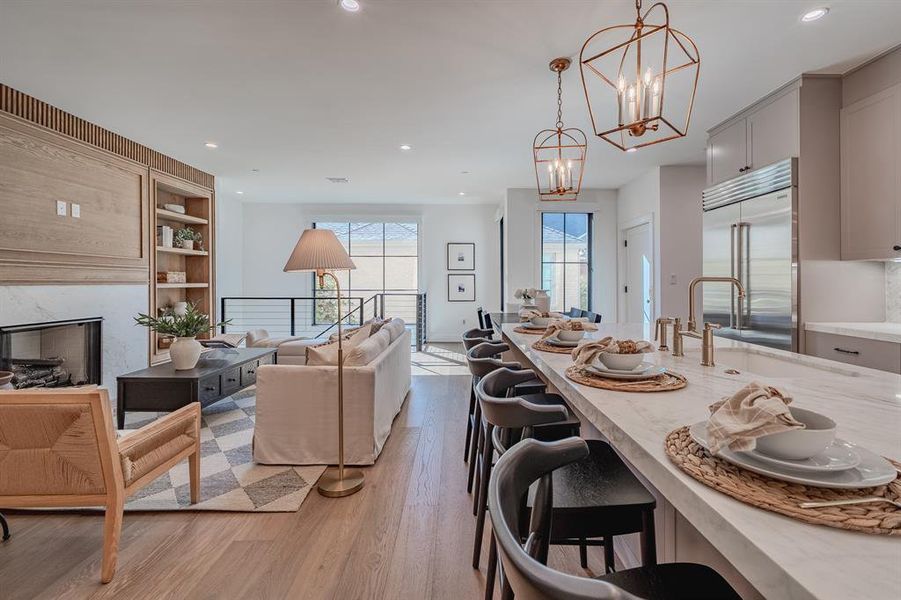 Kitchen featuring decorative light fixtures, light wood-style floors, a breakfast bar area, built in shelves, and recessed lighting Kitchen featuring decorative light fixtures, light wood-style floors, a breakfast bar area, built in shelves, and recessed lighting