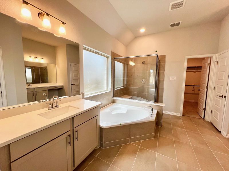 Full bath featuring a stall shower, a walk in closet, a bath, light tile patterned floors, and vanity Full bath featuring a stall shower, a walk in closet, a bath, light tile patterned floors, and vanity