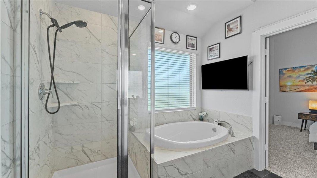 Bathroom with a marble finish shower, a bath, recessed lighting, and dark tile patterned flooring Bathroom with a marble finish shower, a bath, recessed lighting, and dark tile patterned flooring