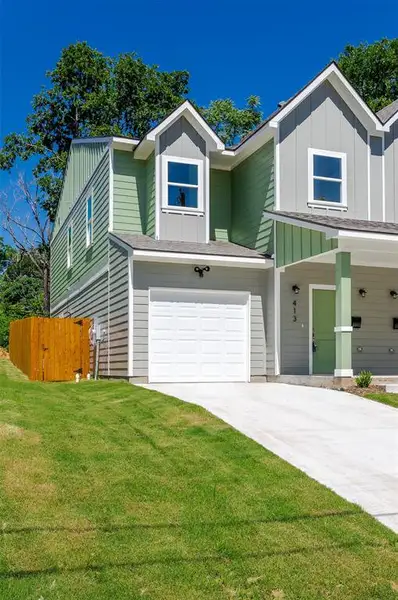 View of front of property featuring a garage and a front lawn