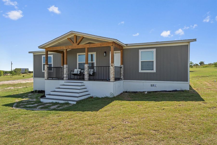 Manufactured / mobile home with covered porch, crawl space, a front lawn, and stairs