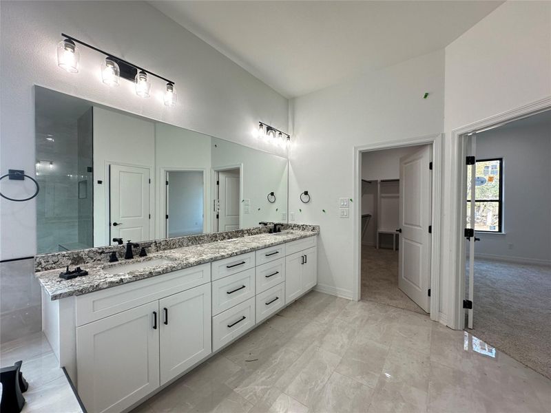Full bath featuring double vanity, a walk in closet, and a stall shower