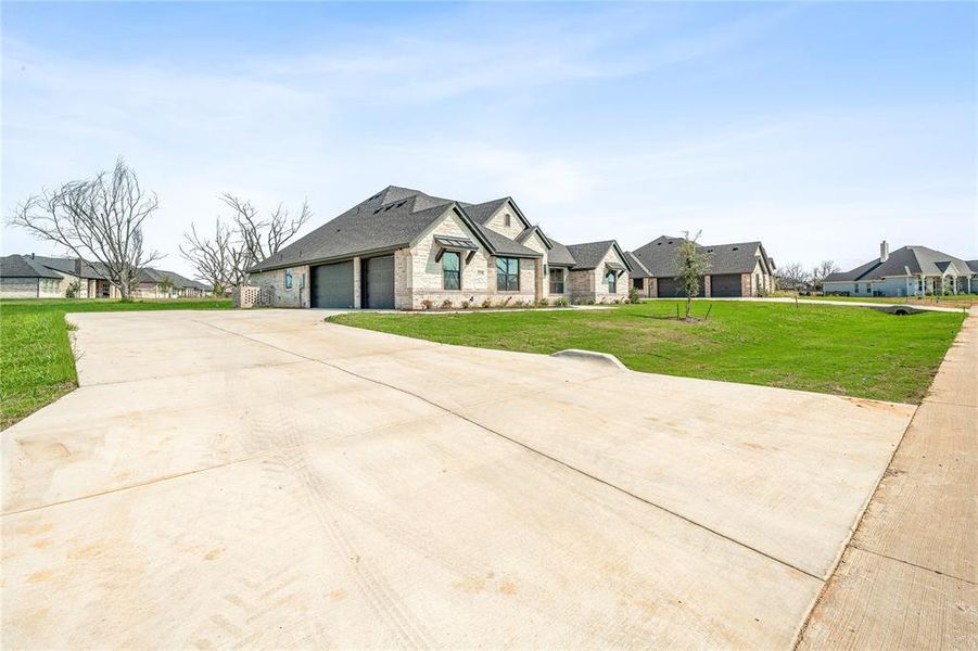 View of front facade with stone siding, concrete driveway, a garage, and a front yard View of front facade with stone siding, concrete driveway, a garage, and a front yard