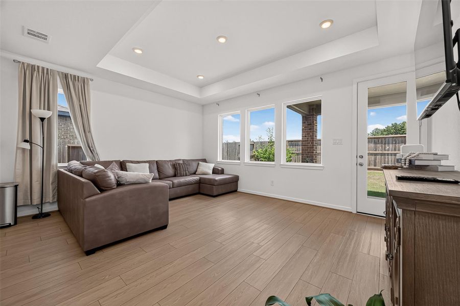 Spacious living room with elegant tray ceiling and abundant natural light from large windows.