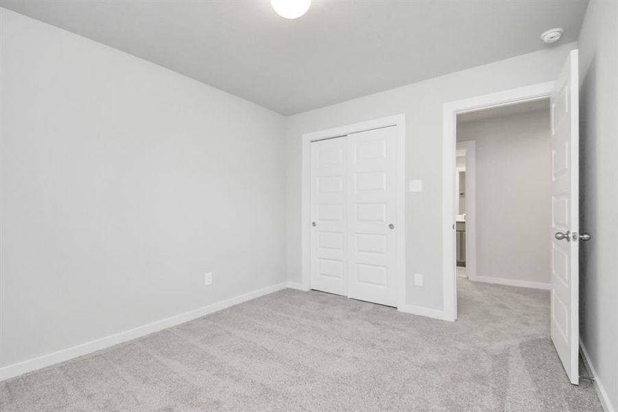 A cozy secondary bedroom with large windows, plush carpet, and spacious closets. The natural light and neutral colors create a serene, inviting atmosphere.