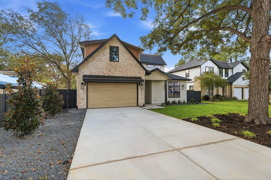 View of front of home with driveway, a garage, and brick siding