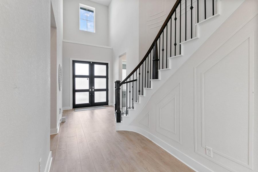 Bright and welcoming entryway featuring soaring ceilings, abundant natural light, and elegant finishes. The open staircase and modern front door design create a grand first impression as you step inside.