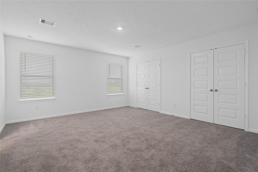 Head upstairs to the primary bedroom where you can relax and recharge! Enjoy the comfort of plush carpeting, neutral toned walls, high ceilings, recessed lighting, and windows that fill the room with natural light.
