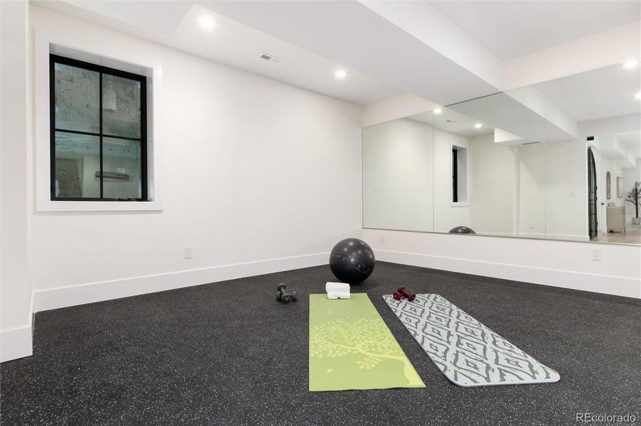 Dedicated workout room with wall to wall mirrors and rubber flooring Dedicated workout room with wall to wall mirrors and rubber flooring
