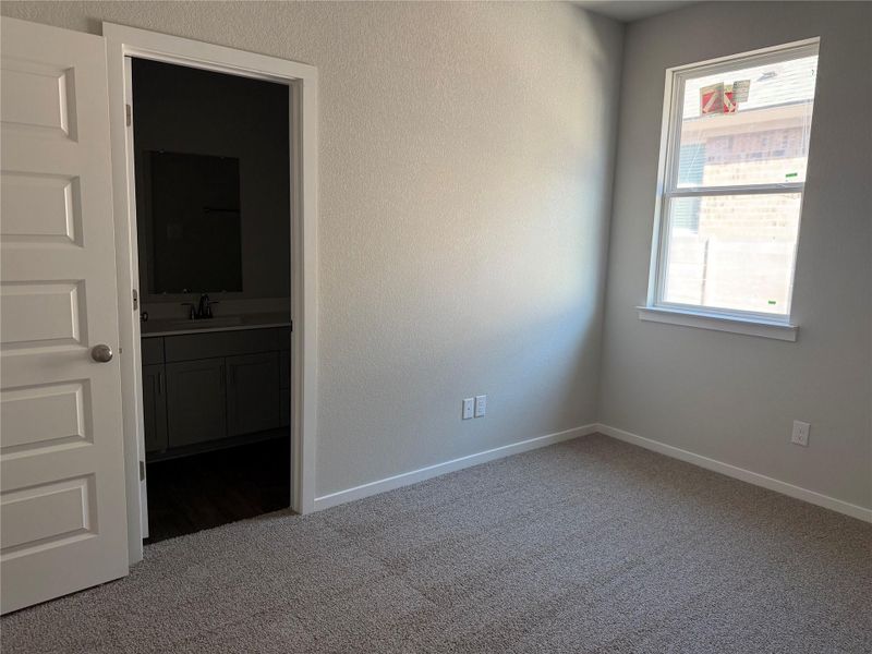 Plush carpeting and a large window define this bedroom with direct bathroom access.