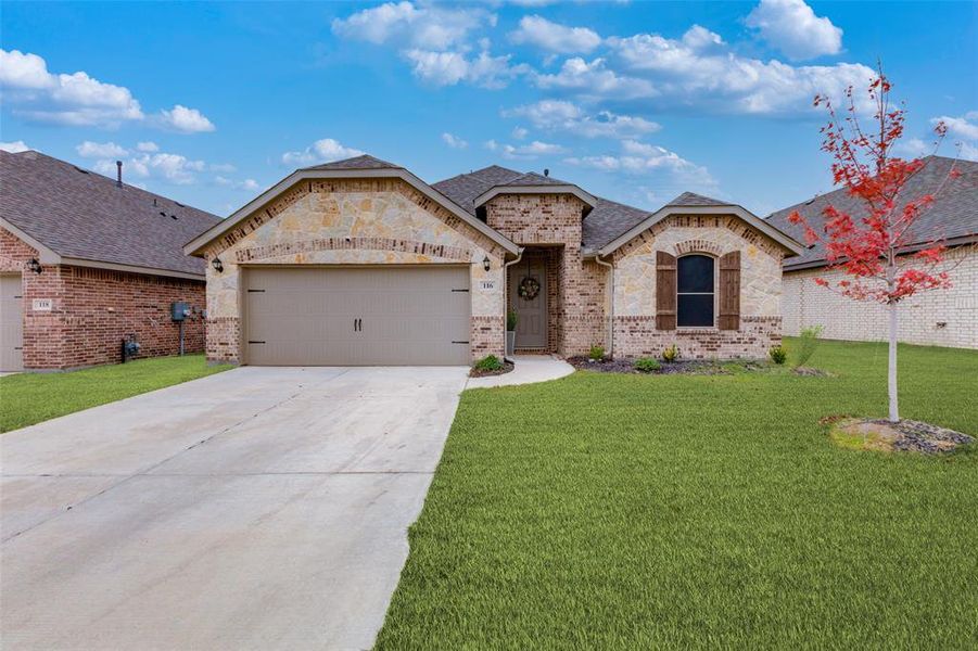 View of front facade featuring a garage and a front lawn