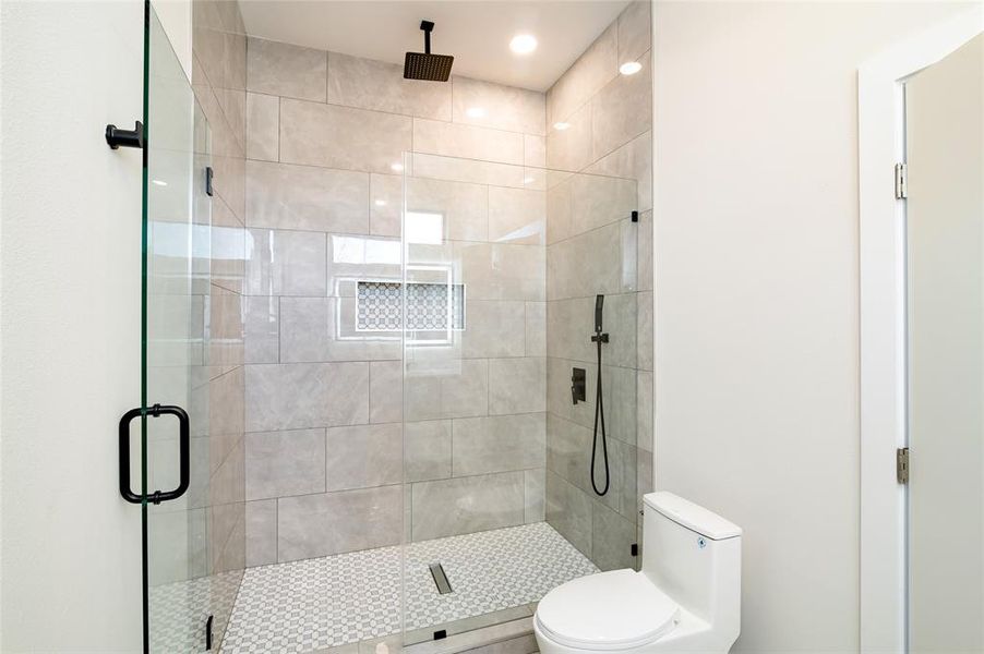 Bathroom featuring toilet and a shower with door