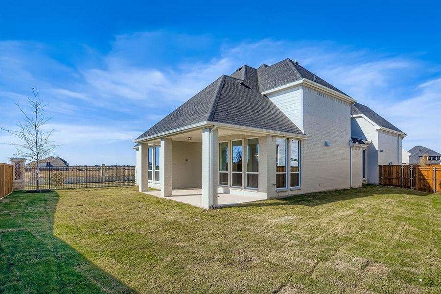 Rear view of property with a shingled roof, a patio area, a fenced backyard, and brick siding