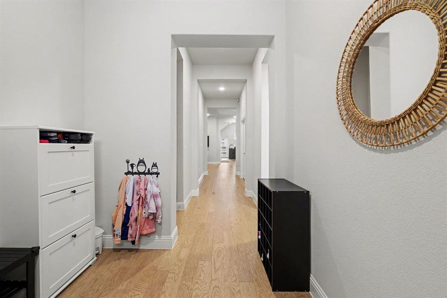 Long hallway featuring wood-finish flooring, light gray walls, and white baseboards