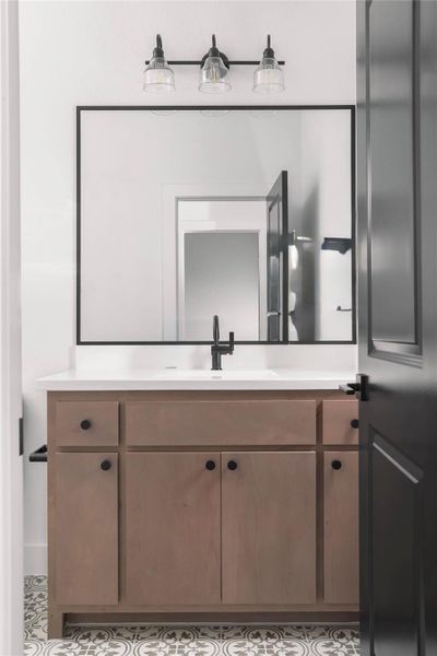 Bathroom vanity with a light wood-finish base, white countertop, and integrated sink