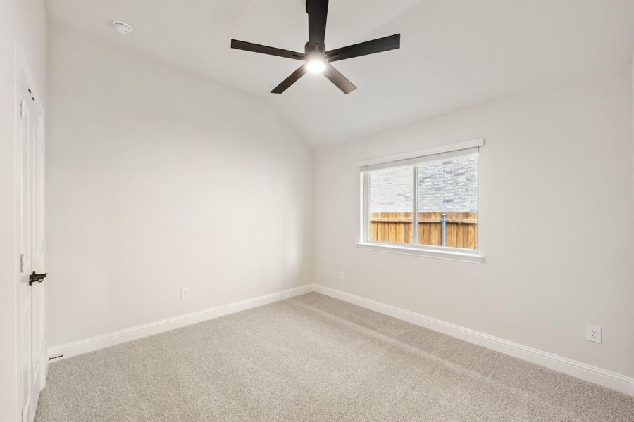 Empty bedroom with gray carpet, vaulted ceiling, black ceiling fan, and single window Empty bedroom with gray carpet, vaulted ceiling, black ceiling fan, and single window