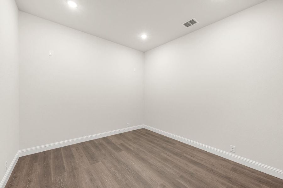Empty room with white walls, recessed lighting, and dark wood-look vinyl plank flooring Empty room with white walls, recessed lighting, and dark wood-look vinyl plank flooring