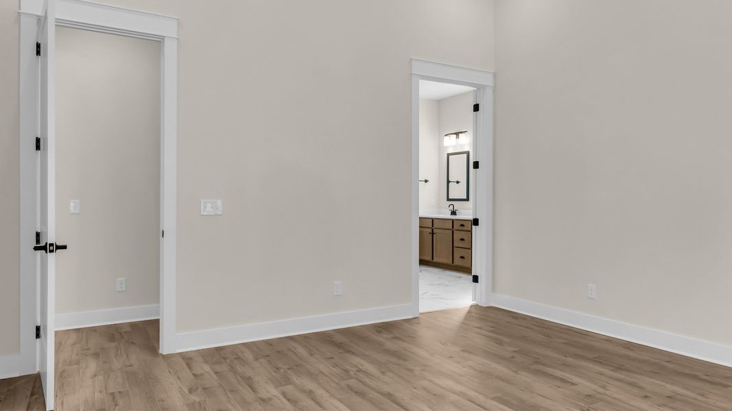 Primary bedroom with wood flooring and en-suite bathroom and an extra walk-in closet. (Representative of completed home)