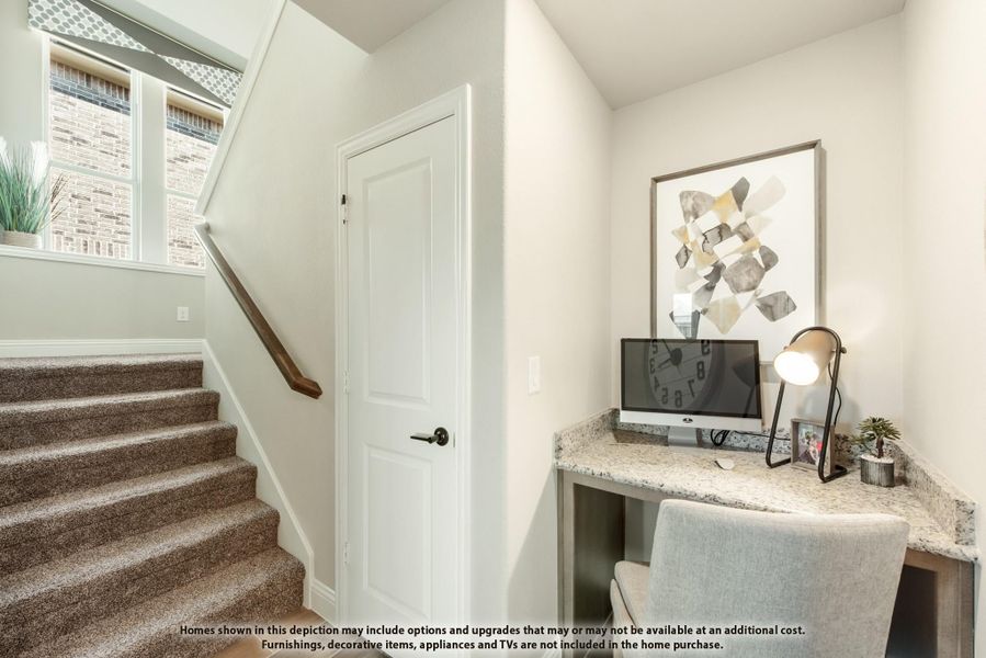 Built-in desk nook with granite countertop beside carpeted staircase and white door