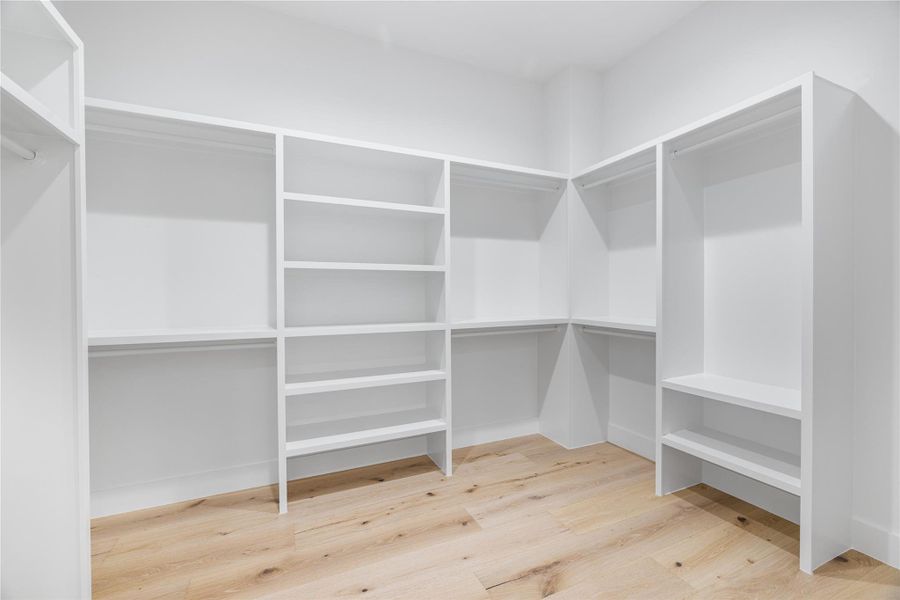 Primary bedroom walk in closet with engineered white oak wood floors Primary bedroom walk in closet with engineered white oak wood floors