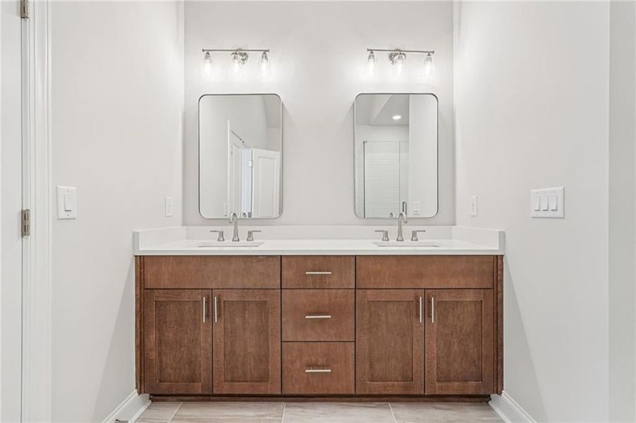 Owners retreat bathroom features driftwood Bell cabinets with quartz top-upgraded light fixtures and framed mirrors finish out this space