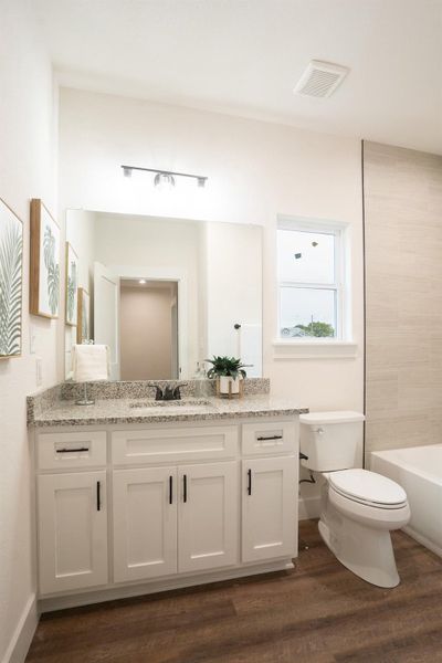 Bathroom featuring vanity, toilet, wood finished floors, and baseboards