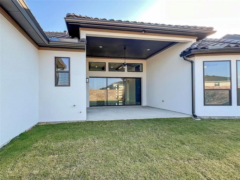 Rear view of house featuring ceiling fan, a patio area, and a yard