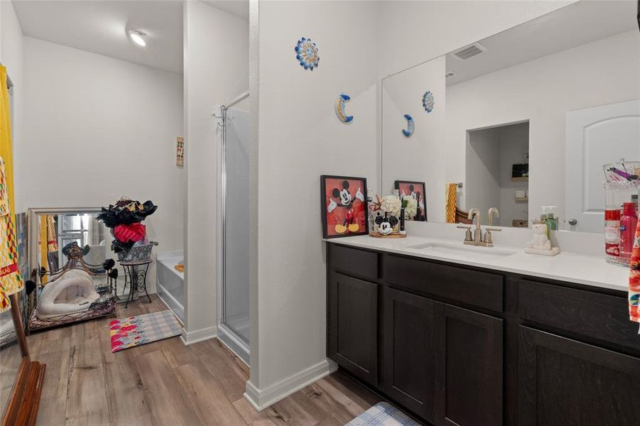 Bathroom featuring a shower stall, light wood-style flooring, vanity, and a garden tub