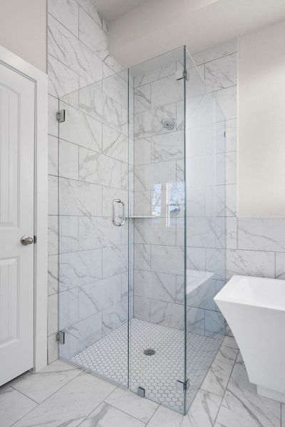 Gleaming glass enclosure and marble-look tile create a modern, minimalist bathing space. Gleaming glass enclosure and marble-look tile create a modern, minimalist bathing space.