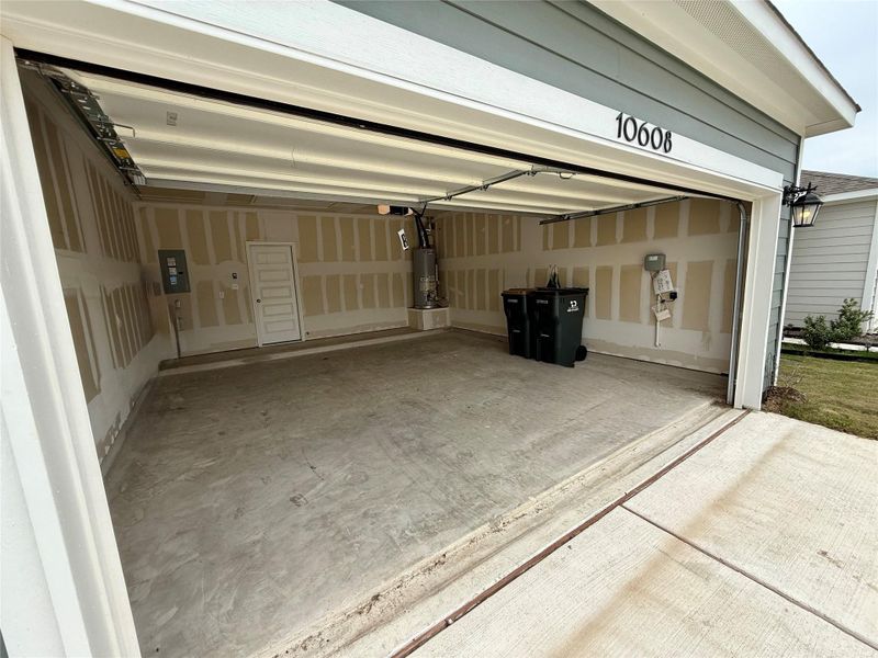 Two-car garage with concrete flooring, automatic garage door opener, and interior access door