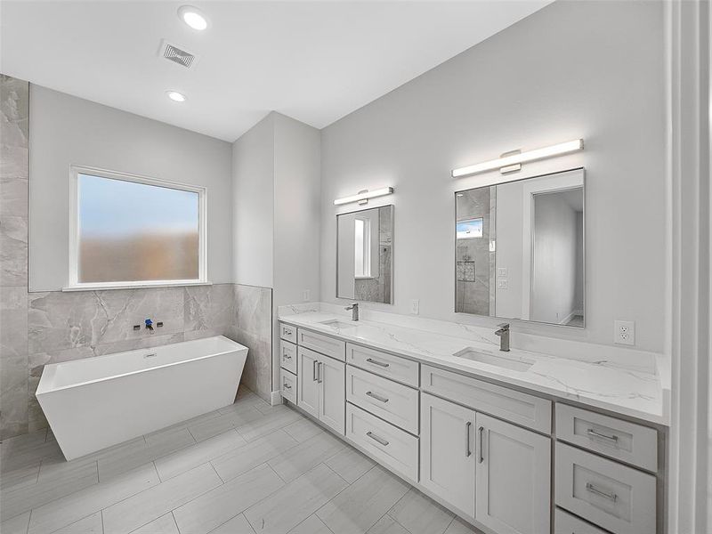 Primary Bath featuring a wealth of natural light, dual bowl vanity, tile patterned floors, and tile walls