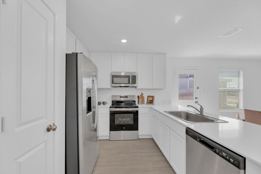Open kitchen with stainless steel appliances, white cabinets, recessed lighting, a peninsula, and light vinyl.  flooring
