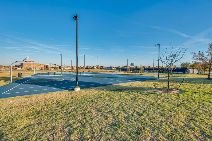 View of tennis court featuring community basketball court, a lawn, and a residential view