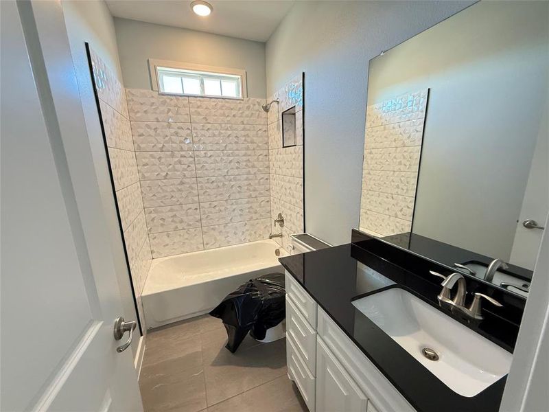 Bathroom featuring tiled shower / bath, vanity, and tile patterned floors