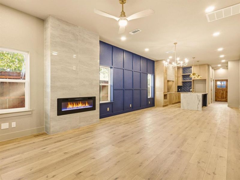 Unfurnished living room with a tiled fireplace, plenty of natural light, light wood-type flooring, a ceiling fan, and recessed lighting