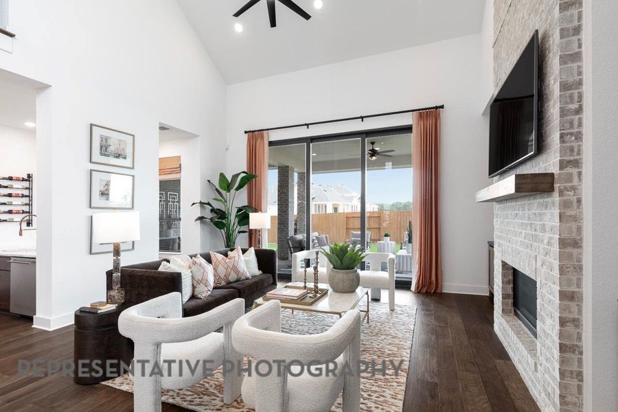 Living area with ceiling fan, a brick fireplace, dark wood-style floors, high vaulted ceiling, and recessed lighting
