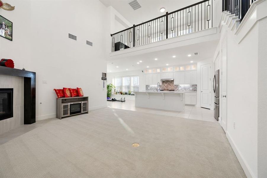 Living area featuring light carpet, a fireplace, a high ceiling, and recessed lighting