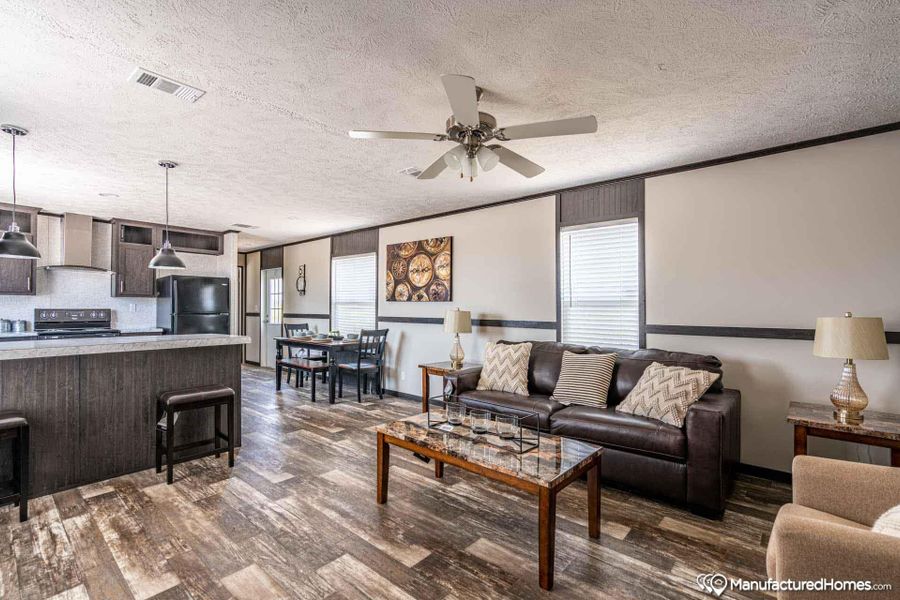 An open concept living area seamlessly blends kitchen, dining, and relaxation spaces on wood-look flooring.