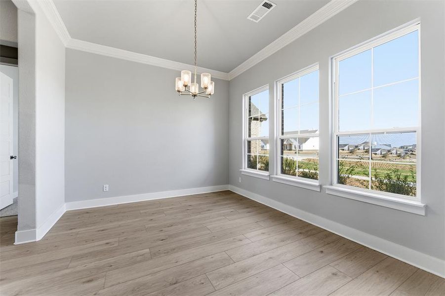 Unfurnished dining area featuring crown molding, a chandelier, and light wood-style floors