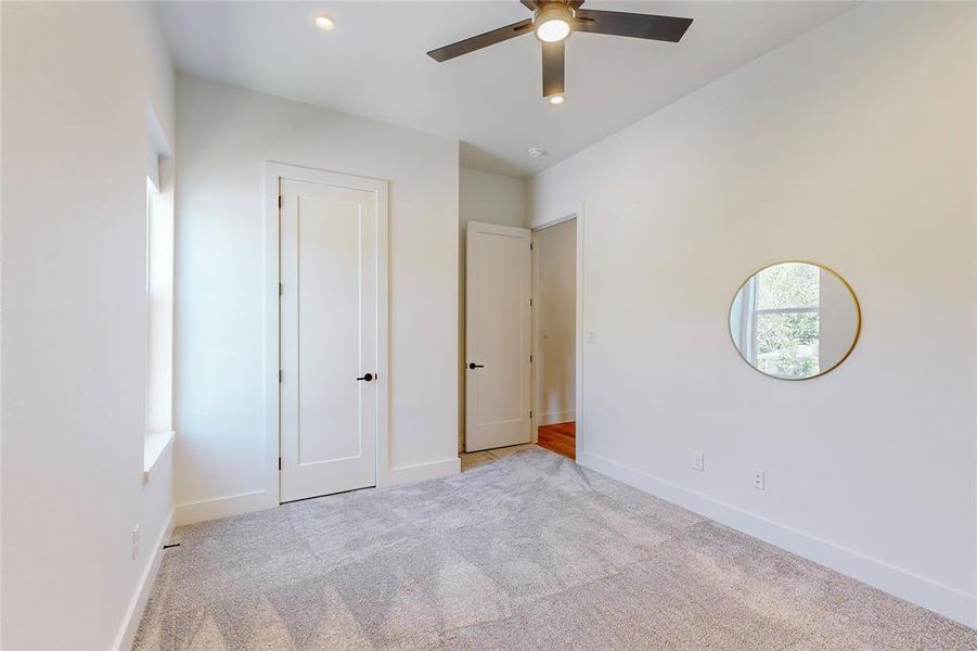 Unfurnished bedroom featuring light carpet and ceiling fan