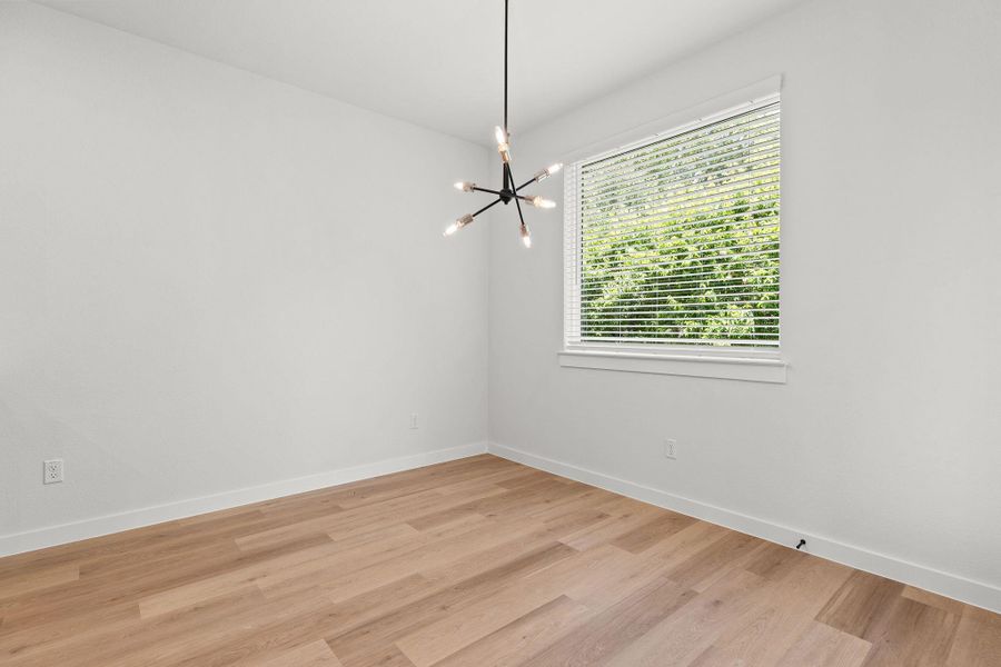 Luminous room featuring polished wood flooring and an elegant contemporary light fixture. Luminous room featuring polished wood flooring and an elegant contemporary light fixture.